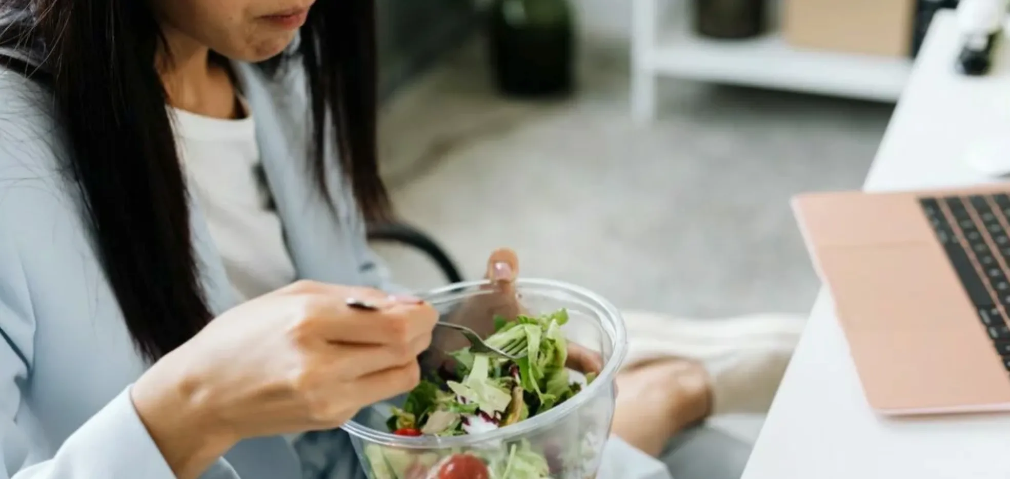Women eating a salad in front of a laptop