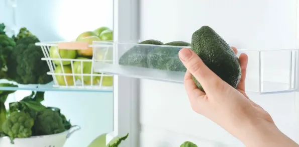 A avocado in front of a fridge