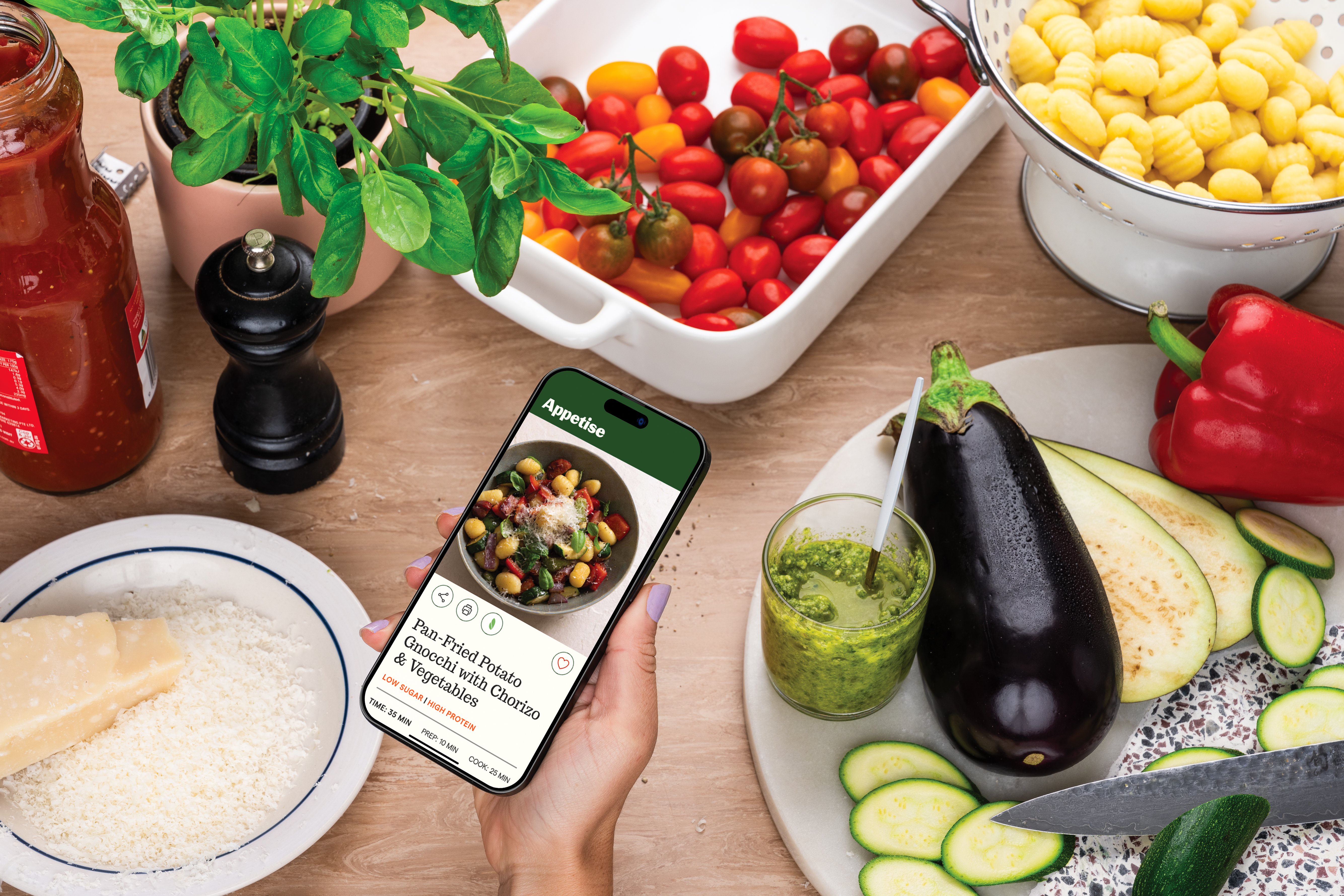 Making person making a vegetable pasta while holding a mobile phone