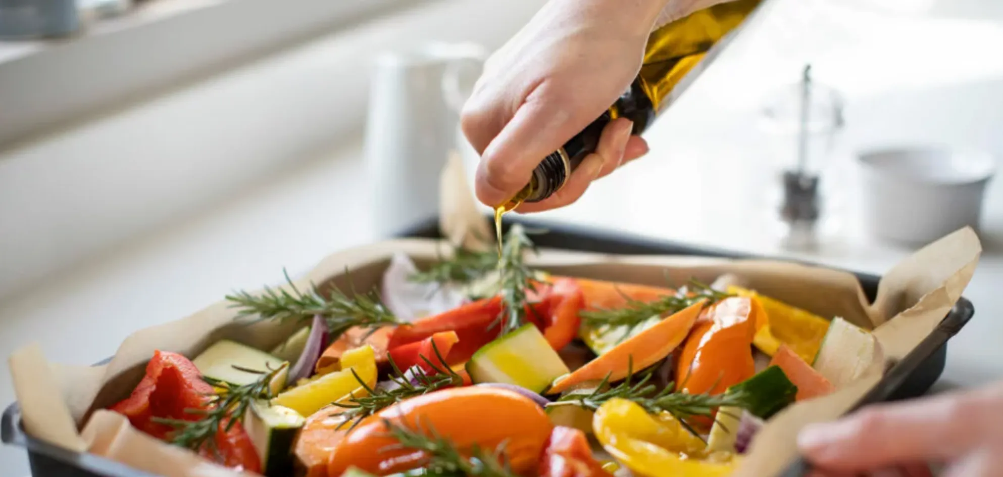 Hand pouring oil on vegetables
